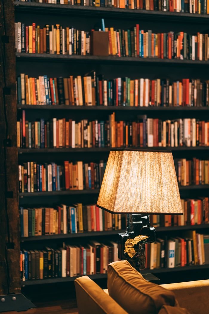 Warmly lit library with bookshelves and a reading lamp creating a cozy ambiance.